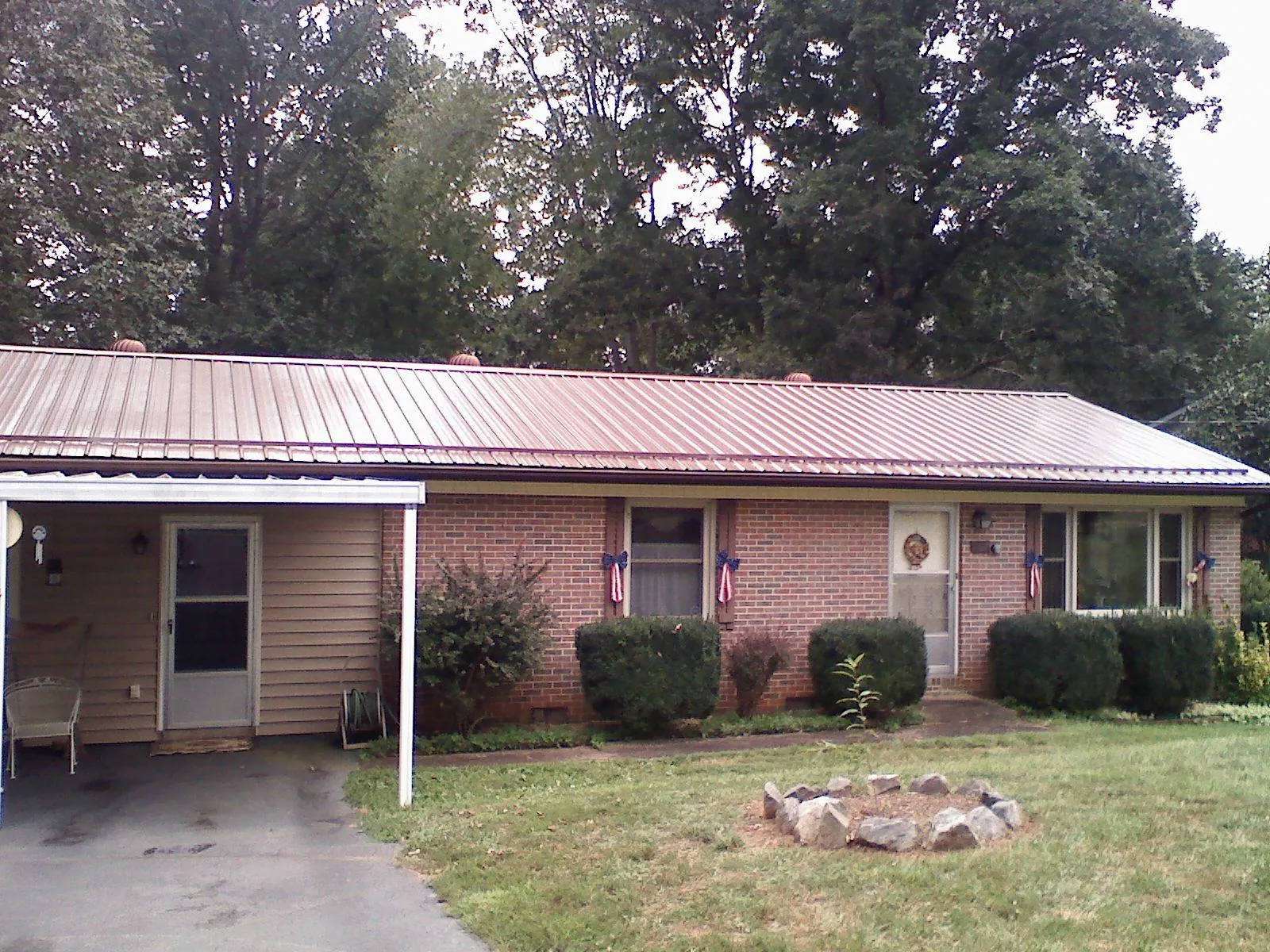 Bronze metal roof and carport on a brick ranch home — Roof Repair work by our crew in Utica